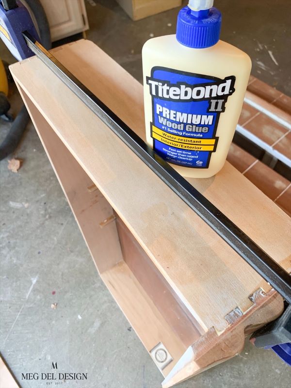 Titebond glue and clamp being used to tighten loose dovetail joints on a dresser to prepare it for paint. 
