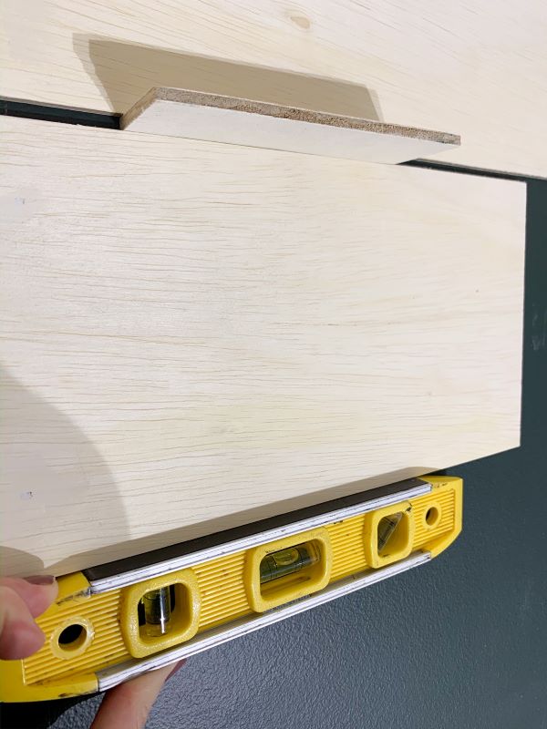 Use a spacer and a level to ensure your plank wall is level before attaching the next board.