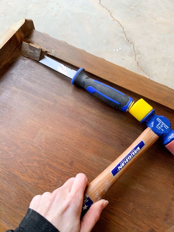 Use a chisel and mallet to remove excess pieces of wood from the side of the vanity that will become painted pink end tables.