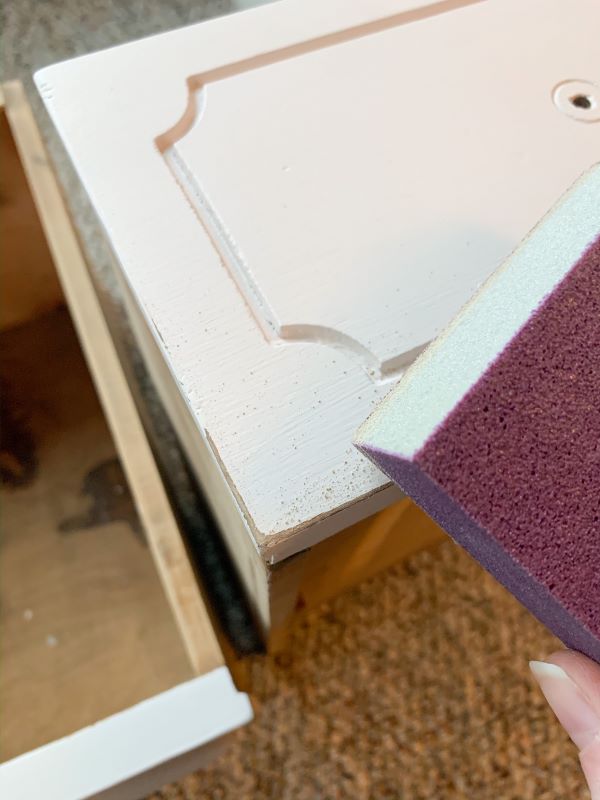Use a 220-grit sanding block to distress the edges of drawers and your painted pink end tables for a distressed look with character