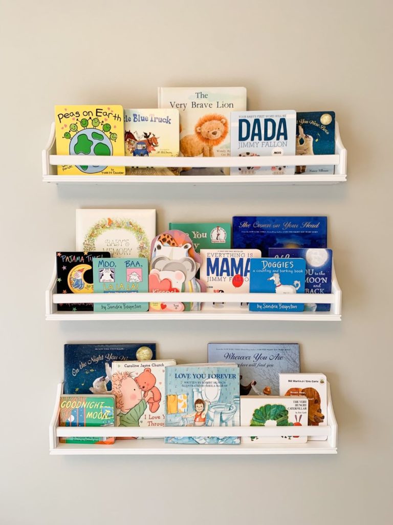 White nursery bookshelves for displaying and storing all of baby boy's books next to his nursing corner.