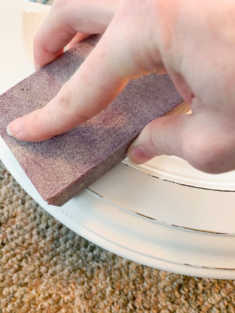 Distress your painted mirror with a 220-grit sanding block to pull back some of the original or wood finish underneath your paint.