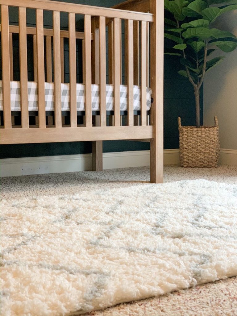 Love this light wood crib with grey and white checkered crib sheet, white and grey shag rug, fiddle leaf tree and wicker basket