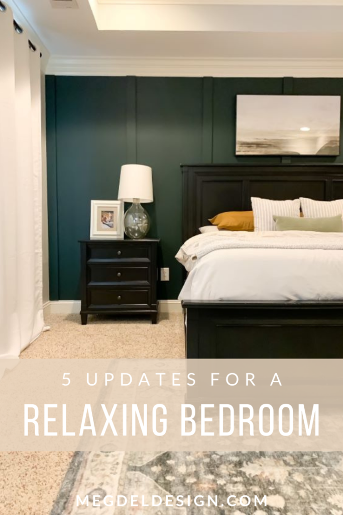 final relaxing master bedroom reveal with dark green board and batten, black bedframe and nightstands, mustard sheets, tan duvet, landscape wall art, modern led ceiling fan. with vintage style rug